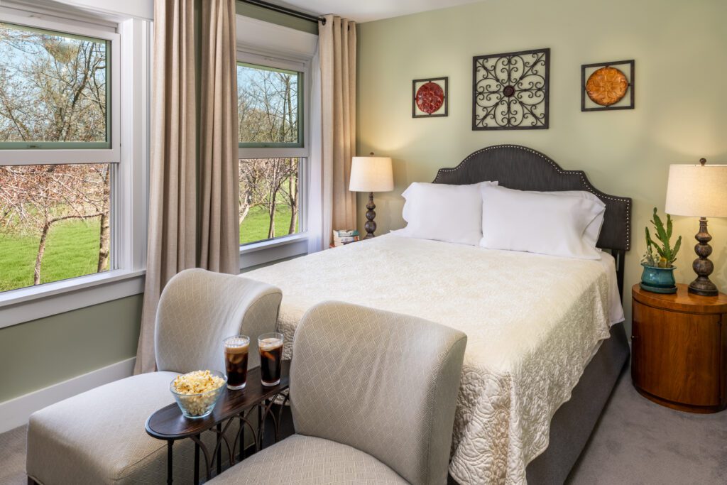 Port_Austin_Bed_and_Breakfast_Port_Austin_Hotel_Room 5-01_Md - Port Austin Bed & Breakfast Image of queen bed with white bedspread and two chairs in front of bed at Port Austin Bed and Breakfst in room 5.