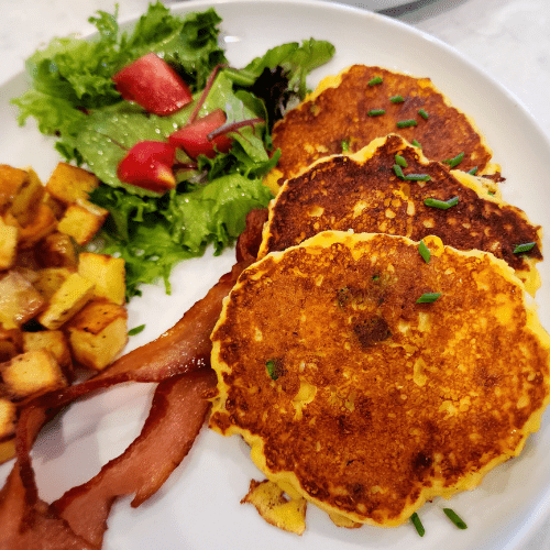 Image of potato corn fritter pancakes, bacon, hashbrowns, and salad