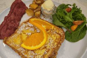 Port_Austin_Bed_and_Breakfast_Port_Austin_Michigan_Hotel_Image - Port Austin Bed & Breakfast French Toast topped with a slice of orange, sausage, potatoes and salad